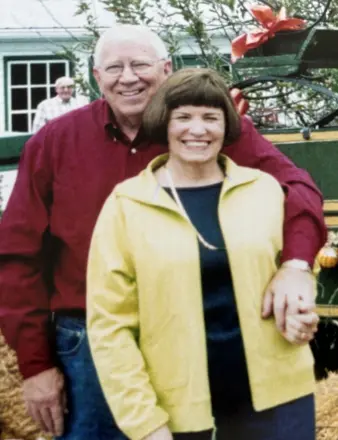 Smiling couple posing outdoors in front of house