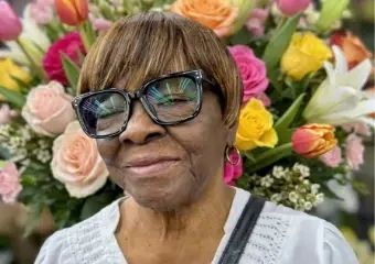 Smiling woman with glasses before colorful flowers