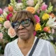Smiling woman with glasses before colorful flowers
