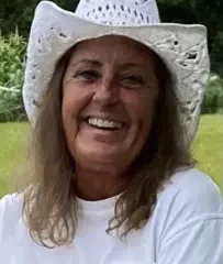 Smiling woman in white cowboy hat holding puppy