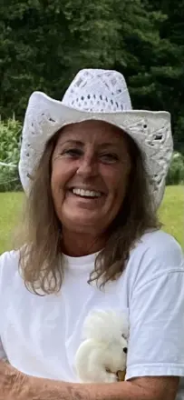 Smiling woman in white cowboy hat holding puppy