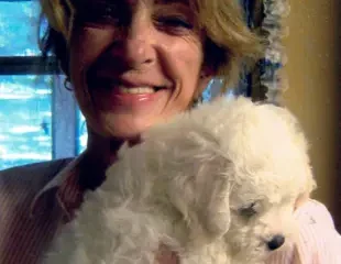 Woman holding fluffy white puppy indoors