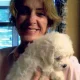 Woman holding fluffy white puppy indoors