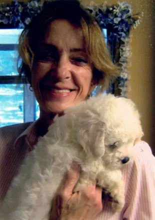 Woman holding fluffy white puppy indoors