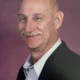 Smiling bald man with mustache in blazer