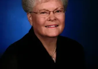 Smiling older woman with glasses against blue background