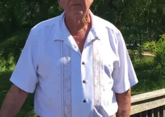 Older man standing outdoors by wooden railing