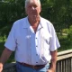 Older man standing outdoors by wooden railing