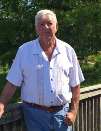 Older man standing outdoors by wooden railing