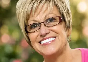 Smiling woman with short blonde hair and glasses