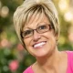 Smiling woman with short blonde hair and glasses