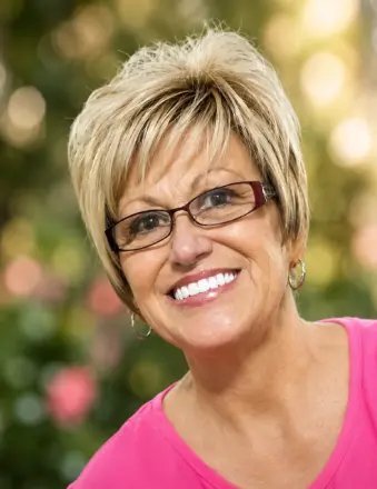 Smiling woman with short blonde hair and glasses
