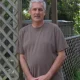 Man standing by wooden lattice fence outdoors