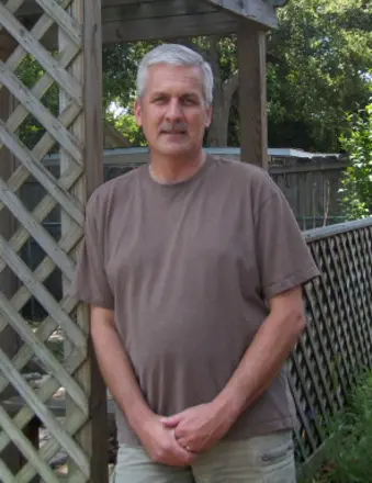 Man standing by wooden lattice fence outdoors