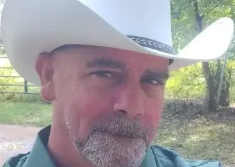 Man wearing white cowboy hat outdoors