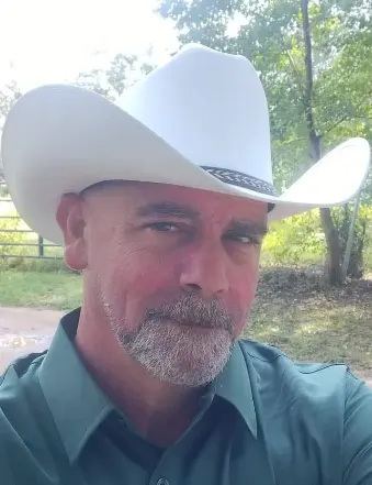 Man wearing white cowboy hat outdoors