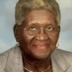 Elderly woman wearing glasses and gray blazer