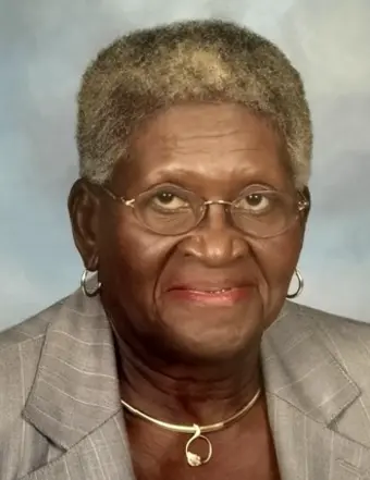 Elderly woman wearing glasses and gray blazer