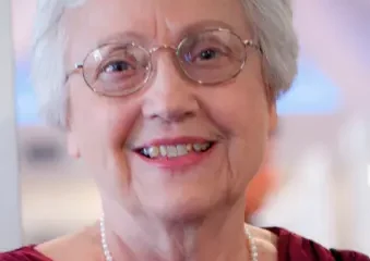 Smiling elderly woman with glasses and pearl necklace