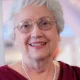 Smiling elderly woman with glasses and pearl necklace