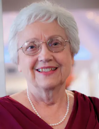Smiling elderly woman with glasses and pearl necklace