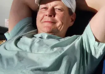 Man relaxing in chair wearing baseball cap indoors