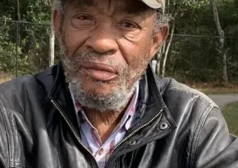 Older man wearing cap and leather jacket outdoors