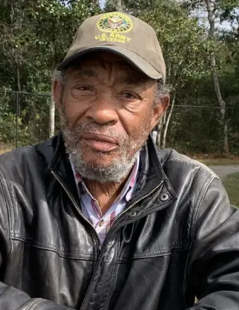 Older man wearing cap and leather jacket outdoors
