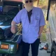 Bearded man leaning on green Jeep in driveway