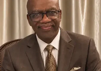 Man in brown suit smiling indoors