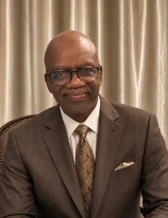 Man in brown suit smiling indoors