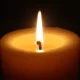 Lit candle with glowing flame in darkness