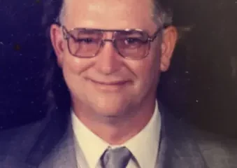 Man in suit with glasses and lapel pin