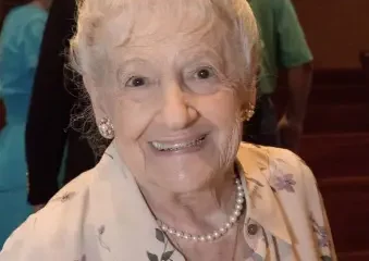 Smiling elderly woman wearing floral blouse and pearls