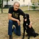 Man kneeling beside black dog in yard