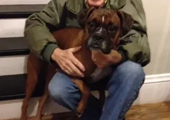Elderly man hugging brown boxer dog indoors