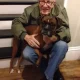 Elderly man hugging brown boxer dog indoors