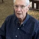 Elderly man wearing glasses and plaid shirt indoors
