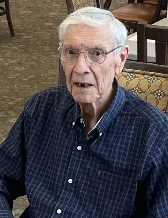 Elderly man wearing glasses and plaid shirt indoors