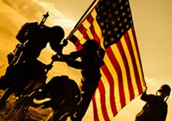 Soldiers raising American flag at sunset silhouette
