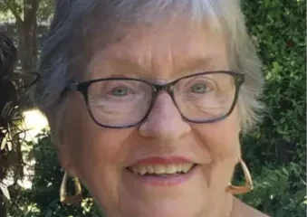 Smiling elderly woman with glasses outdoors