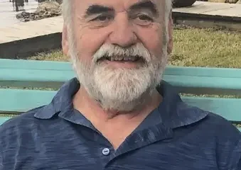 Smiling older man sitting on bench by water