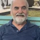 Smiling older man sitting on bench by water
