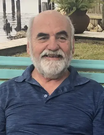 Smiling older man sitting on bench by water
