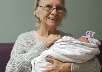 Elderly woman holding a newborn baby indoors