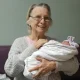 Elderly woman holding a newborn baby indoors