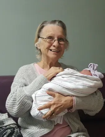 Elderly woman holding a newborn baby indoors