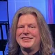 Smiling person with long hair in studio setting