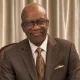 Man in brown suit smiling indoors