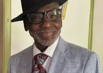 Smiling man in gray suit and black hat